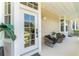Inviting front porch features comfortable seating, a charming table, and a welcoming entrance with glass paneled door at 152 Riggings Way, Clermont, FL 34711