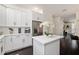 Open kitchen with white cabinets, quartz countertop, island, and stainless steel fridge at 152 Riggings Way, Clermont, FL 34711