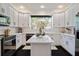 Bright kitchen boasts white cabinetry, sleek black appliances, stone countertops, and center island beneath recessed lighting at 152 Riggings Way, Clermont, FL 34711