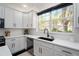 White kitchen with stainless steel appliances, quartz countertops, a black faucet and a large window at 152 Riggings Way, Clermont, FL 34711