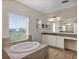 A luxurious bathroom boasts a soaking tub with a scenic outdoor view from a large window at 15769 Shorebird Ln, Winter Garden, FL 34787