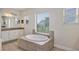 Elegant bathroom showcasing a soaking tub, neutral tile, and natural light from two windows at 15769 Shorebird Ln, Winter Garden, FL 34787