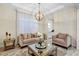 Cozy living room features a mirrored coffee table, neutral furniture, and open access to the kitchen at 15769 Shorebird Ln, Winter Garden, FL 34787