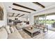 Open-concept living room with wood beam ceiling, tile floors, and access to the kitchen and outdoor patio at 15769 Shorebird Ln, Winter Garden, FL 34787