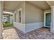 Inviting covered porch with a brick paver floor, elegant columns, and a stylish front door at 15769 Shorebird Ln, Winter Garden, FL 34787