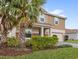Well-maintained two-story home with lush landscaping and tall palm trees in a vibrant community, with a two car garage at 1640 Oak Blossom Dr, Davenport, FL 33837