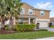 Well-maintained two-story home with lush landscaping and tall palm trees in a vibrant community, with a two car garage at 1640 Oak Blossom Dr, Davenport, FL 33837