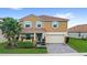 Charming two-story home showcasing a well-manicured lawn, a two-car garage, and a welcoming front porch at 1640 Oak Blossom Dr, Davenport, FL 33837