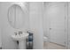 This is a bright half bath with a pedestal sink, oval mirror, and storage at 4071 Isabella Cir, Windermere, FL 34786
