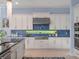 A well-lit kitchen with white cabinets, stainless steel appliances, and a stylish blue tile backsplash at 4071 Isabella Cir, Windermere, FL 34786