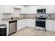 Well-equipped kitchen features white cabinetry, stainless steel appliances, granite countertops, and tile flooring at 440 Patricia Alford Dr, Haines City, FL 33844