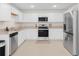 Modern kitchen features white cabinetry, stainless steel appliances, granite countertops, and tile flooring at 440 Patricia Alford Dr, Haines City, FL 33844