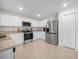 Modern kitchen features white cabinetry, stainless steel appliances, granite countertops, and tile flooring at 440 Patricia Alford Dr, Haines City, FL 33844