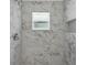 This walk-in shower is beautifully tiled in marble with a window bringing in natural light at 4901 Lindsay Ct, Orlando, FL 32821