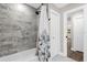 A full tub and shower with elegant tile surround and fixtures and a blue floral curtain at 5 W Village Dr, Oviedo, FL 32765