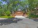 Exterior facade featuring mature trees, landscaping, & two car garage at 5 W Village Dr, Oviedo, FL 32765