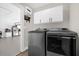 Well-equipped laundry room with modern washer and dryer, overhead storage, and utility sink at 5 W Village Dr, Oviedo, FL 32765