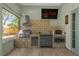 Cozy outdoor kitchen equipped with a grill, stovetop, microwave, and a TV with Netflix at 5 W Village Dr, Oviedo, FL 32765