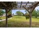 Backyard view from under the pergola featuring lush greenery, trees and sprawling grass at 775 Bay Dr, New Smyrna Beach, FL 32168