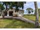 Exterior view of tan barn with a brick paver walkway and landscaping leading to double doors at 775 Bay Dr, New Smyrna Beach, FL 32168