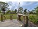 View of the house from the wooden dock featuring a white table and sink, plus a sprawling green lawn and mature trees at 775 Bay Dr, New Smyrna Beach, FL 32168