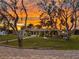 Charming home with pergola and beautiful landscaping, set against a vibrant sunset sky at 775 Bay Dr, New Smyrna Beach, FL 32168
