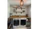 Functional laundry room featuring modern washer and dryer, wooden countertop, and open shelving for storage at 775 Bay Dr, New Smyrna Beach, FL 32168