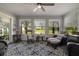 Bright sunroom boasts ample windows, a ceiling fan, comfortable seating, and a stylish area rug at 775 Bay Dr, New Smyrna Beach, FL 32168