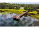 Scenic view of a wooden pier extending into a calm lake, surrounded by lush greenery and blue skies at 8134 Hook Cir, Orlando, FL 32836