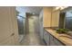 Bright bathroom features a dual sink vanity with granite countertops, tiled floors, and glass enclosed shower at 8930 Zurich Ln, Kissimmee, FL 34747