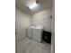 Laundry room with tile floor features a washer, dryer, and overhead wire shelf at 8930 Zurich Ln, Kissimmee, FL 34747