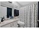 Well-lit bathroom featuring a floral shower curtain, toilet, vanity, and mirror at 9616 River Walk Ct, Orlando, FL 32825