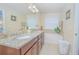 Bright bathroom featuring double sinks with granite counters, soaking tub, and neutral tiling at 10520 Burrows St, Orlando, FL 32832