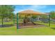 Community playground featuring play structures, a covered seating area, and green space for recreation at 10520 Burrows St, Orlando, FL 32832