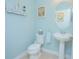 Stylish powder room with pedestal sink, oval mirror, and light blue walls at 10520 Burrows St, Orlando, FL 32832