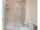 Well-lit shower with glass doors and neutral tile, complete with a mounted shower head and convenient toiletry storage at 10520 Burrows St, Orlando, FL 32832