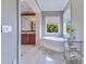 Bright bathroom boasts a soaking tub with a view, dark wood vanity, and stylish marble flooring at 10845 Bayshore Dr, Windermere, FL 34786