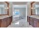 Luxurious bathroom featuring dual vanities, and a soaking tub with serene water views through the window at 10845 Bayshore Dr, Windermere, FL 34786