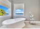 Relaxing bathroom featuring a soaking tub with a scenic lake view from the window at 10845 Bayshore Dr, Windermere, FL 34786