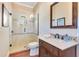 Bathroom with glass shower, dark wood vanity, and wood look tile floor at 10845 Bayshore Dr, Windermere, FL 34786