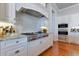 Chef's kitchen with stainless appliances, custom hood, granite counters, custom cabinets, and tile backsplash at 10845 Bayshore Dr, Windermere, FL 34786