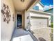 View of the front porch with artistic wall decor, a small potted plant, and a two-car garage at 11868 Thatcher Ave, Orlando, FL 32836