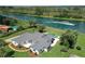 Stunning aerial view of a waterfront home with a pool and lush landscaping, featuring boaters enjoying the water at 12508 Lake Denise Blvd, Clermont, FL 34711