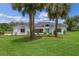 Charming home exterior showcasing a lush lawn, mature palm trees, and a welcoming turquoise front door at 12508 Lake Denise Blvd, Clermont, FL 34711
