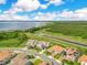 Aerial view of homes with red tile roofs and well-manicured lawns with a lake in the background at 13791 Abberwick Dr, Orlando, FL 32832