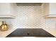 Close-up of the kitchen backsplash with elegant gold accents, modern cooktop, and plenty of lighting at 13791 Abberwick Dr, Orlando, FL 32832