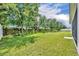 View of the large backyard with lots of green grass, bushes and beautiful trees at 14325 Hidden Ct, Clermont, FL 34711