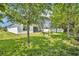 This is a large backyard with lots of green grass and mature trees, and a view of the exterior at 14325 Hidden Ct, Clermont, FL 34711
