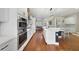 Spacious kitchen features stainless appliances, white cabinetry, island with seating, and hardwood floors at 14525 Englert Aly, Orlando, FL 32827