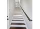 Elegant staircase with hardwood treads, white risers, and a sleek, dark handrail leading upstairs at 14525 Englert Aly, Orlando, FL 32827
